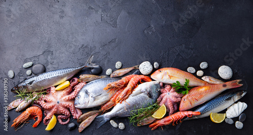 Fresh fish and seafood assortment on black slate background. Copy space. Top view. photo