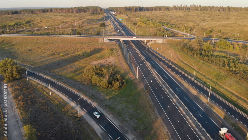 aerial view. Interchange on the intercity highway. Cars and trucks travel in different directions. Two stripes in each direction.