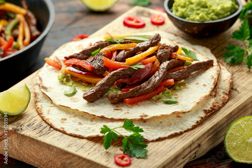 Beef Steak Fajitas with tortilla mix pepper, onion and avocado on wooden board