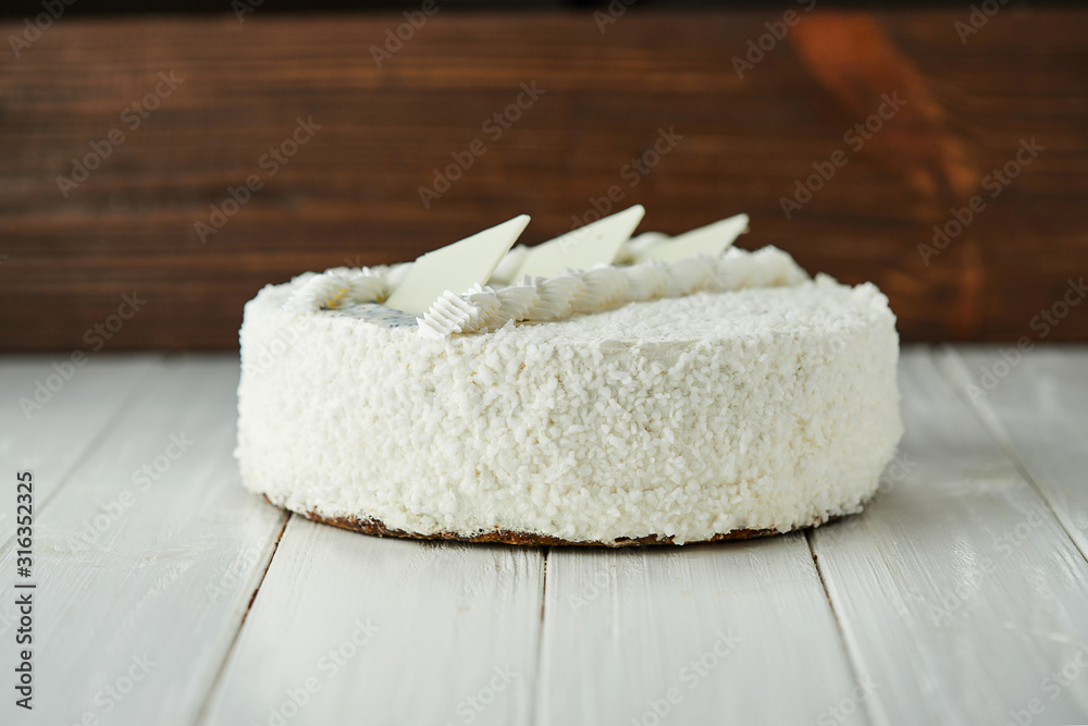 Birthday cake with white chocolate, butter cream and poppy seed biscuit on wooden background
