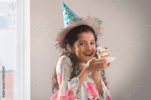 Portrait of a young girl eating her birthday cake. (Children)  	
