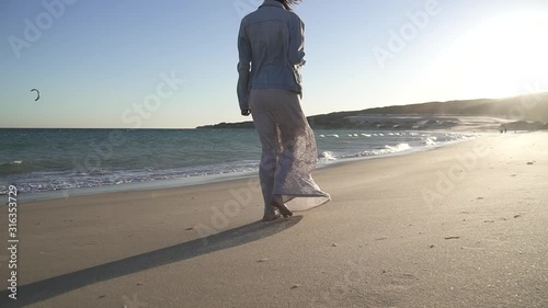 Mujer sola con vestido paseando por la playa en el atardecer HD