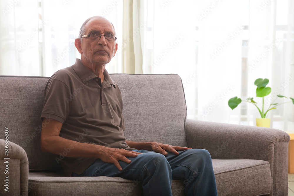 Portraits of a senior man sitting on couch at home. 