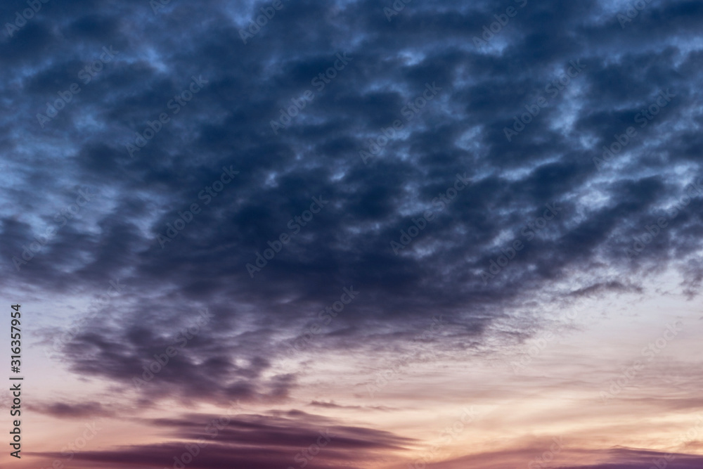 Dark cumulus clouds float through the sky before sunrise.