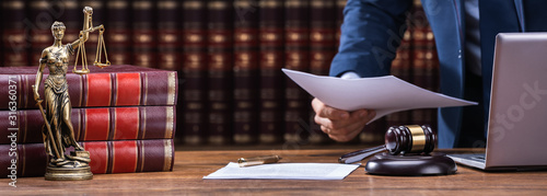 Fotografie Lawyer Holding Documents Near Mallet And Laptop