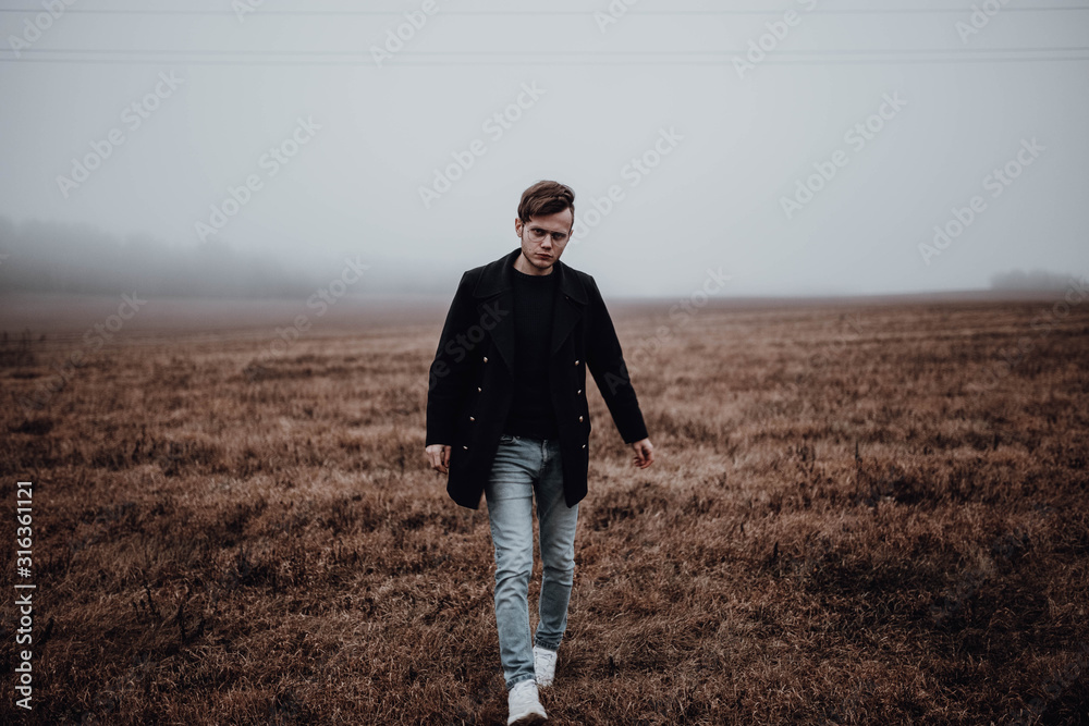 Lonely man in a coat of jeans and sneakers in a red field in cold weather. Lonely man in a coat of jeans and sneakers in a red field in cold weather.