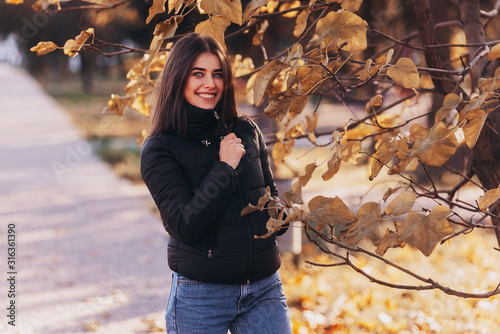 Portrait of beautiful charming smiling woman. Woman in black coat outdoor © VlaDee