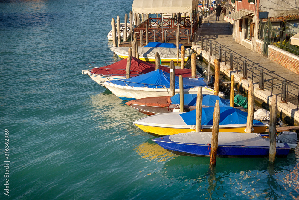 Motor boats anchored in colorful shopping street in Venice, Italy.