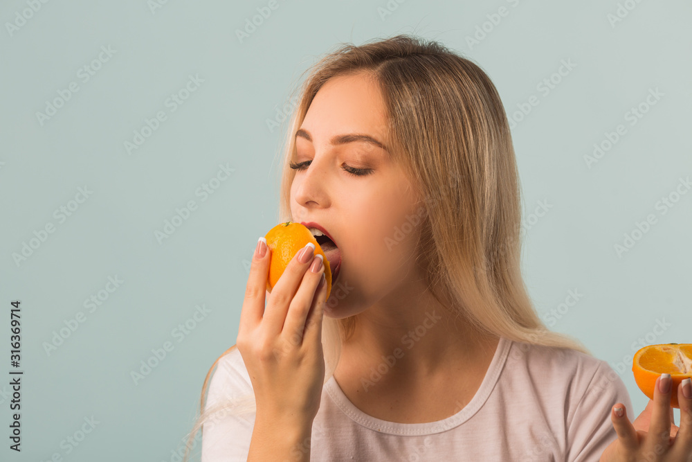 beautiful young woman with orange in hands on a blue background beautiful young woman with orange in hands on a blue background