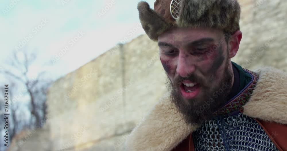 Tired chieftain with malice killing enemy with sword after fight at camera