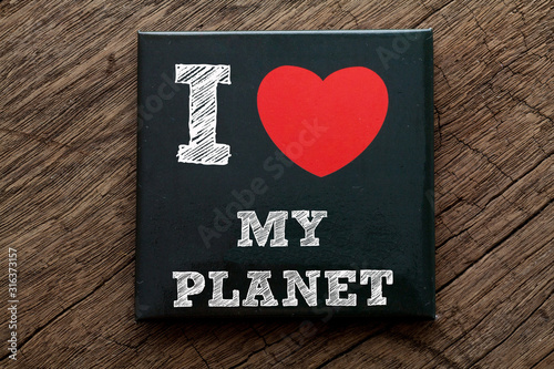 I Love My Planet written on black note with wood background