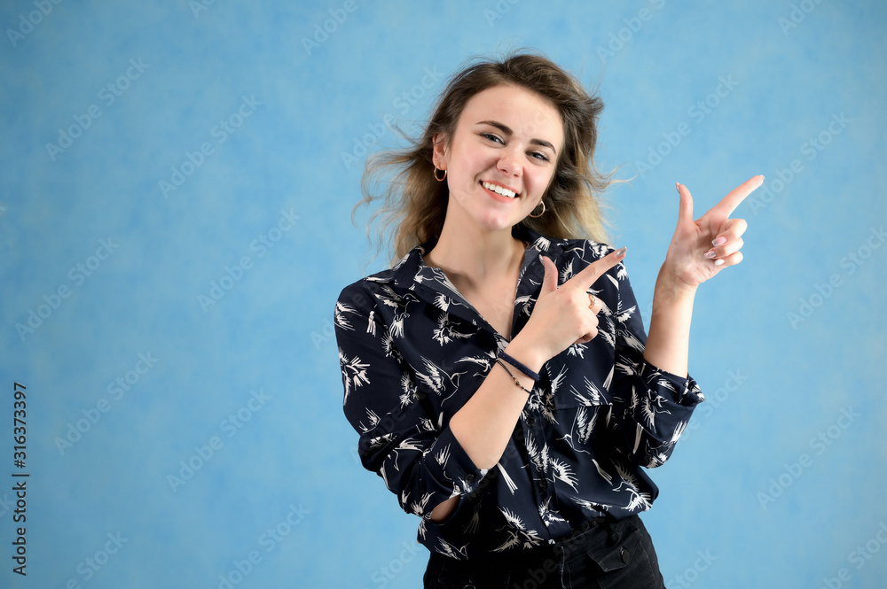 Concept woman in a dark blouse smiling talking. Portrait of a model girl with excellent makeup with curly hair and good teeth in the studio on a blue background. Concept woman in a dark blouse smiling talking. Portrait of a model girl with excellent makeup with curly hair and good teeth in the studio on a blue background.