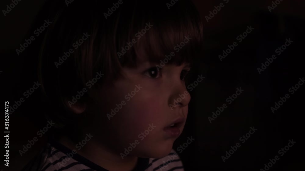 Portrait Сute Little Kid While Watching TV. Young Boy Watch Television on Living Room. Concept Video Game, Entertainment, Emotions, Family. Child Watching TV, Close up Face of Little Boy, Kid Eyes. Portrait Сute Little Kid While Watching TV. Young Boy Watch Television on Living Room. Concept Video Game, Entertainment, Emotions, Family. Child Watching TV, Close up Face of Little Boy, Kid Eyes.