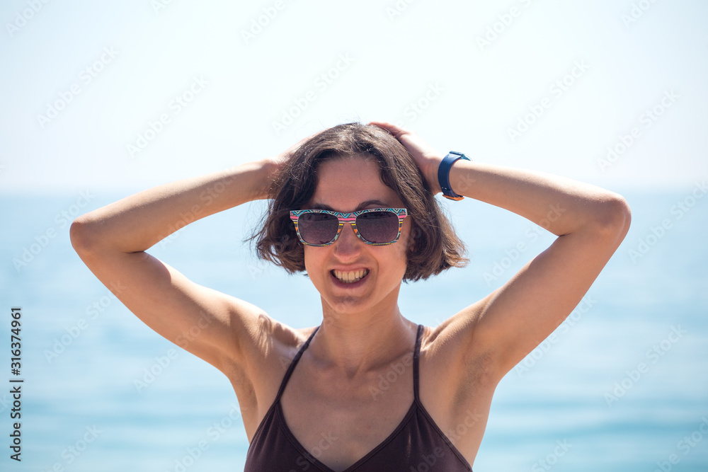 A smiling woman is standing on the seashore.