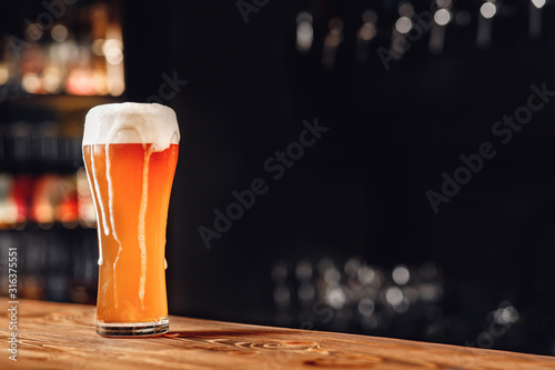 Fresh light beer with foam wooden pub counter, dark background