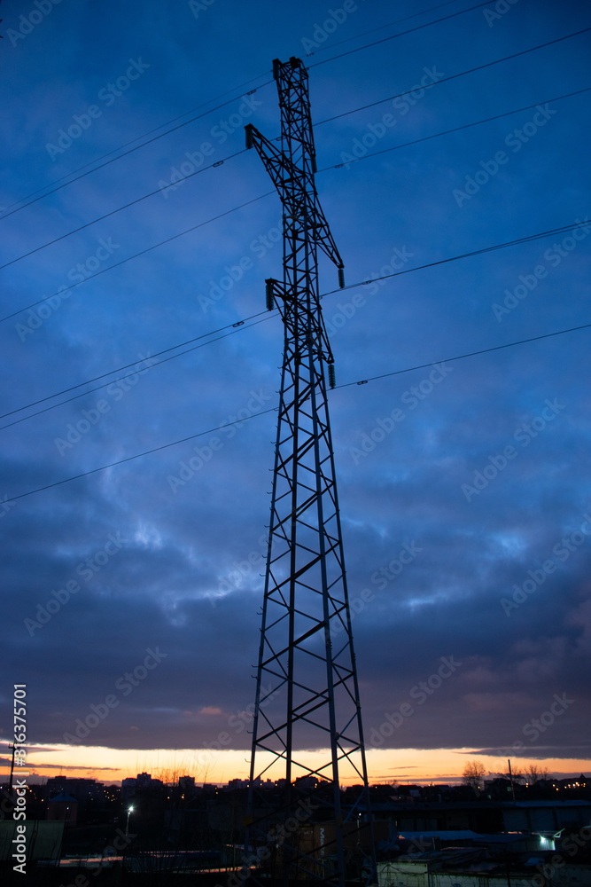 Silhouette of a pylon with blue sky and sunrise in the background