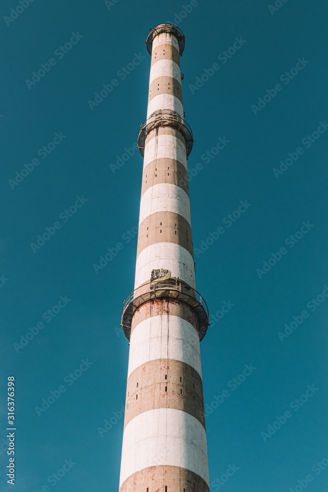 Industrial factory chimney against blue sky, vintage film edit
