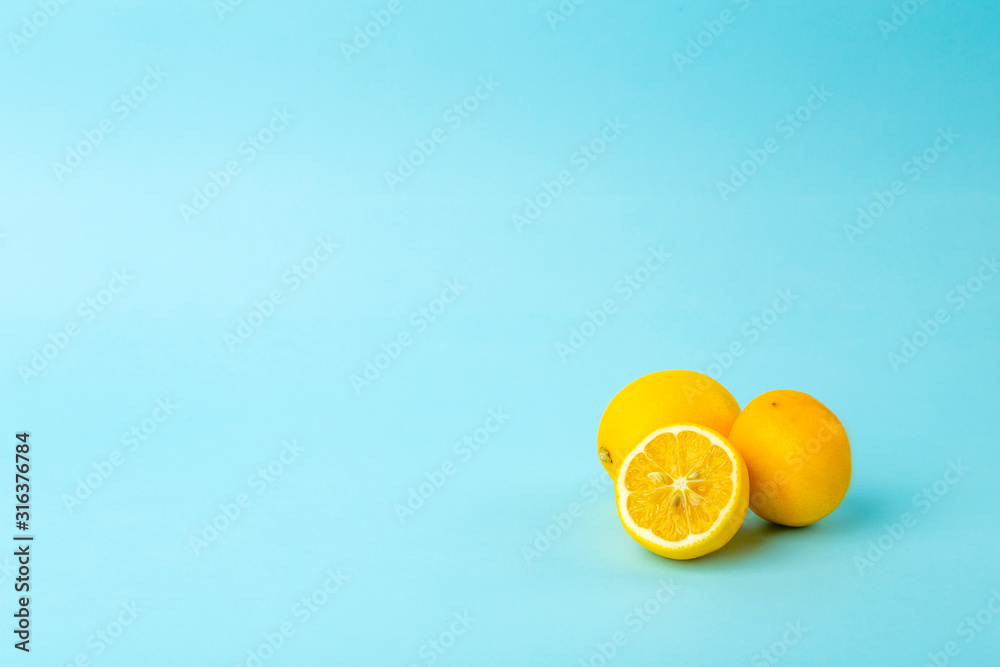 Fototapeta Summer and vitamins background. Lemon on a blue background, minimal food concept