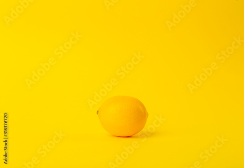 Summer and vitamins background. Lemon on a yellow background, minimal food concept