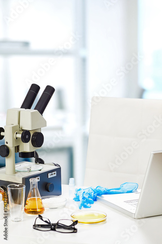 Laboratory table with microscope and chemical glassware