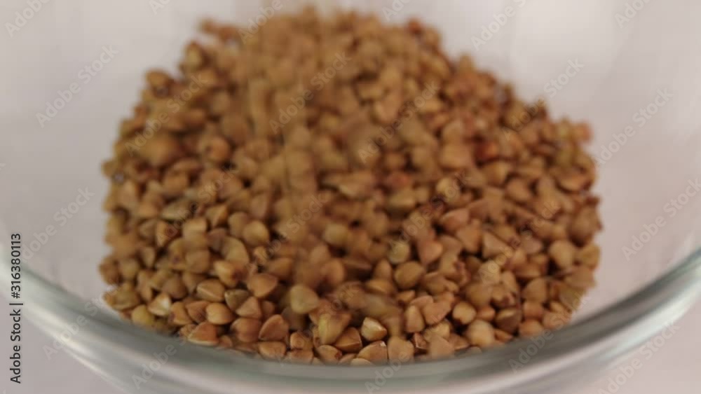 Buckwheat kernels sprinkle in a glass transparent bowl, close-up