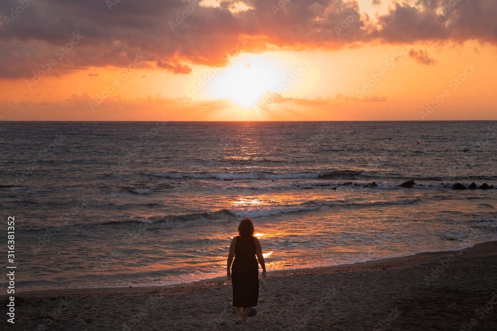 Woman watching the sunrise, sunset from the shore in Nijar, Almeria, Andalusia, Spain.
