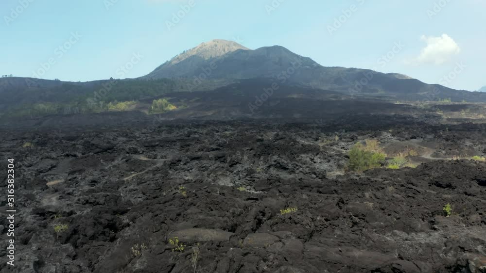 Aerial drone view flying over cold, black volcanic lava flows from an active volcano (Mount Batur, Bali, Indonesia) Aerial drone view flying over cold, black volcanic lava flows from an active volcano (Mount Batur, Bali, Indonesia)