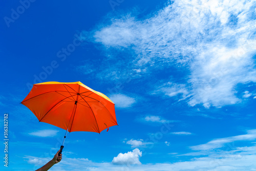 Multicolored of rainbow umbrella in bottom view for protect skin from the sun  high uv on the blue summer sky with white fluffy clound. Freedom in the blue sky.