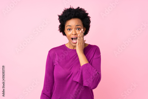 African american woman over isolated pink background with surprise and shocked facial expression