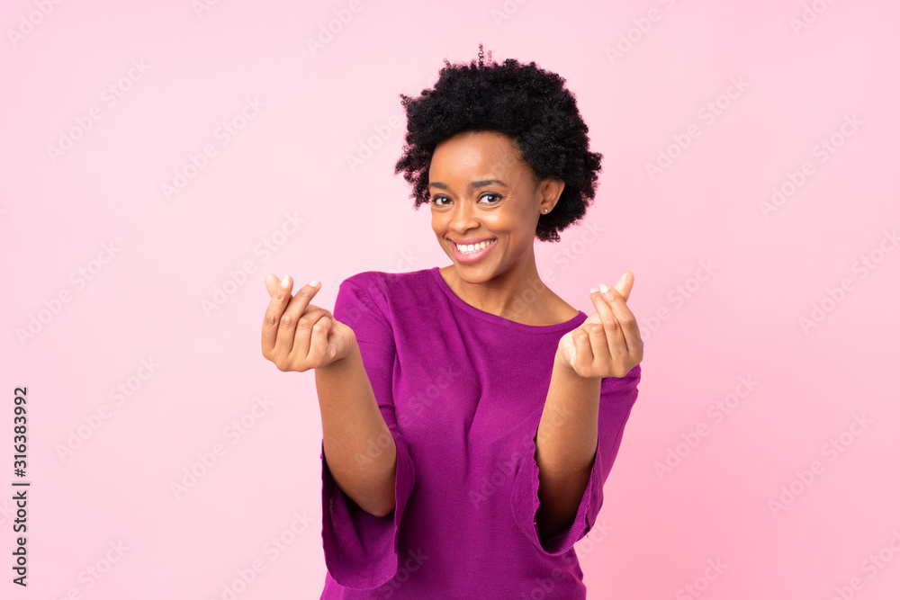 African american woman over isolated pink background making money gesture