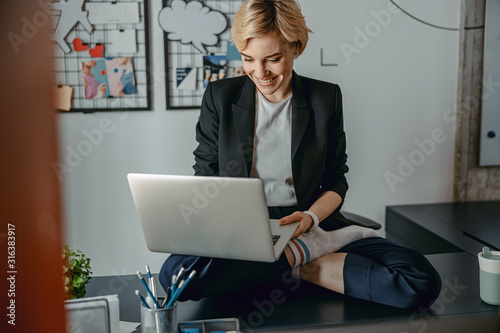 Happy pretty woman sitting on desktop with laptop