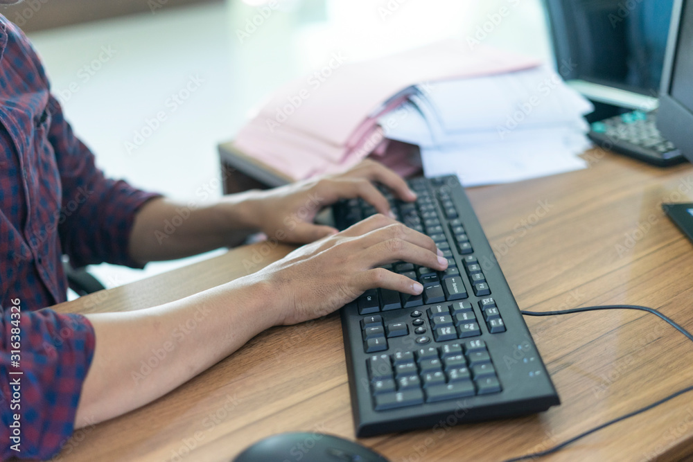 Man working by using a computer on wooden table. Hands typing on a keyboard. Man working by using a computer on wooden table. Hands typing on a keyboard.