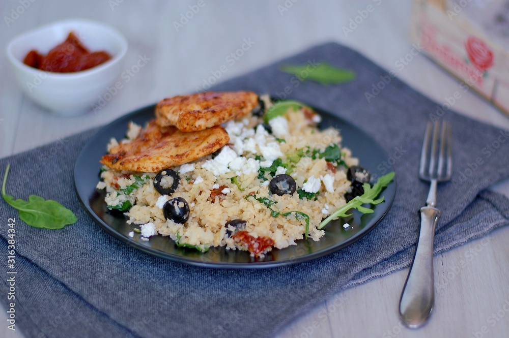 Low carb food chicken fillets white cauliflower rice with dryed tomato, black olive, arugula and cheese Low carb food chicken fillets white cauliflower rice with dryed tomato, black olive, arugula and cheese
