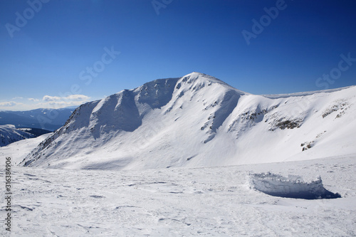 Snowy wall against the background of the mountains © Vitalfoto