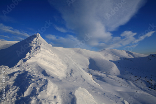 The bright blue sky above the snow-covered slopes of the mountains © Vitalfoto