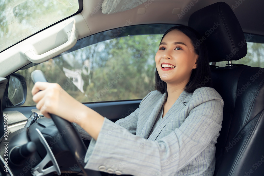 Safety driving concept, Smiling happy young Chinese Thai Asian businesswoman driving a car in town, Confident and beautiful girl. Rear view woman in business suit wear looking over her shoulder Safety driving concept, Smiling happy young Chinese Thai Asian businesswoman driving a car in town, Confident and beautiful girl. Rear view woman in business suit wear looking over her shoulder