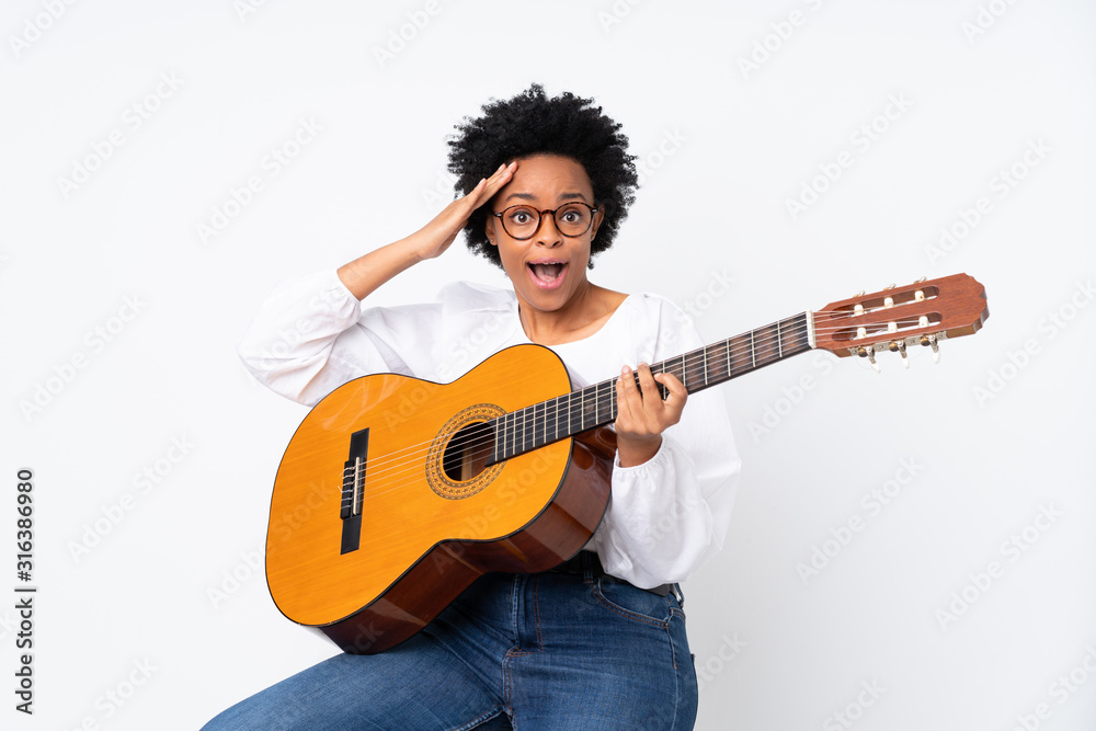 African american woman with guitar over isolated background with surprise and shocked facial expression