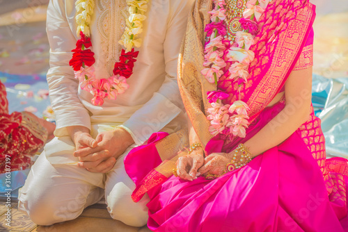 The bride and groom sit on the floor at an Indian wedding ceremony.