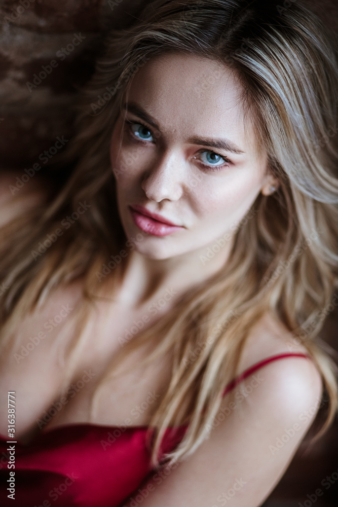 Beautiful blonde woman in a silk red dress combination posing over loft background. Fashion beauty portrait Beautiful blonde woman in a silk red dress combination posing over loft background. Fashion beauty portrait