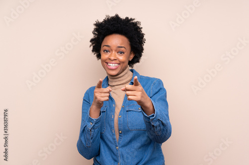 African american woman over isolated background points finger at you
