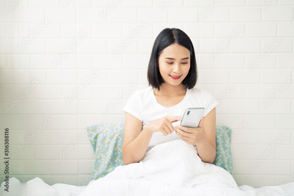 Young Asian woman serving internet she looking a smartphone,messaging texting and smiling while lay on bed in bedroom at home,lifestyle,Social networks for sale product, shopping,fashion Mobile addict Young Asian woman serving internet she looking a smartphone,messaging texting and smiling while lay on bed in bedroom at home,lifestyle,Social networks for sale product, shopping,fashion Mobile addict