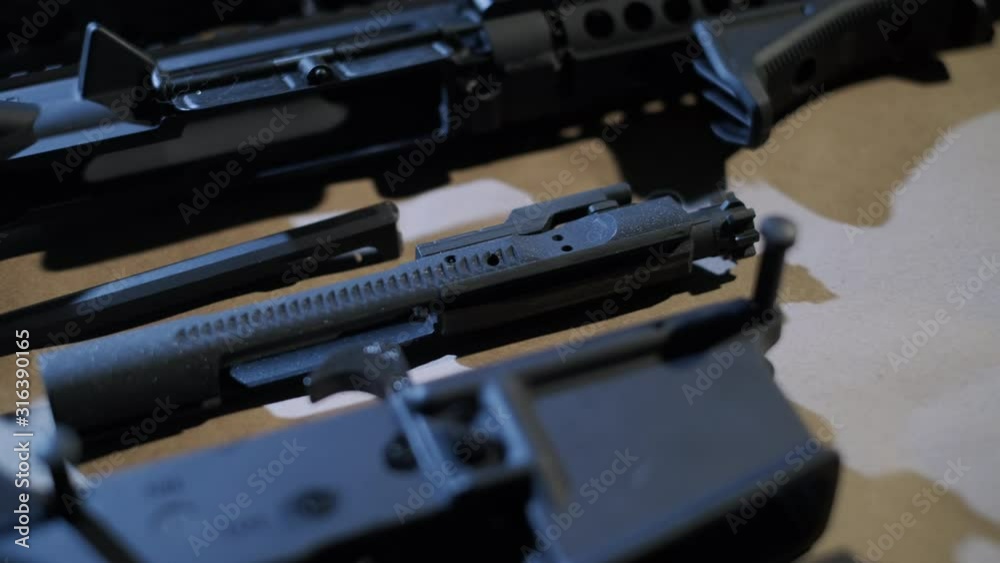 slow pan across disassembled ar-15 rifle in a pistol configuration. The shot slides across the charging handle, the bolt carrier group and the lower assembly.