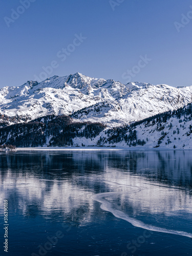 A frozen lake in the engadine, during a sunny winter day in the alps, near the village of Sankt Moritz and Silvaplana, Switzerland - January 2020