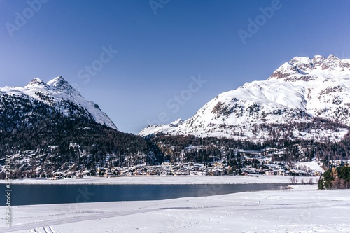 A frozen lake in the engadine, during a sunny winter day in the alps, near the village of Sankt Moritz and Silvaplana, Switzerland - January 2020 photo