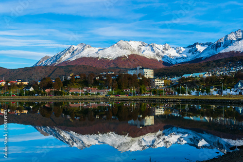 Colorful scene view of the bay and Ushuaia city against snow capped Andes mountains during autumn season © Pedro Suarez