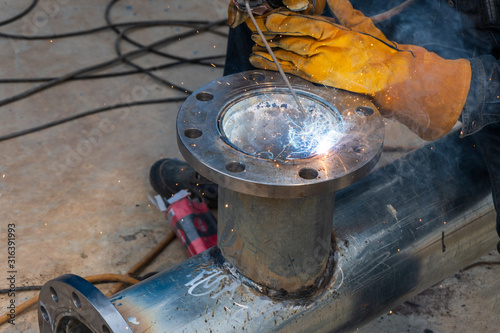 The welder is welding the flange of the suction pipe of the water pump. photo