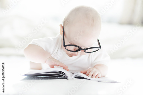 A newborn baby is lying on a soft bed in glasses.