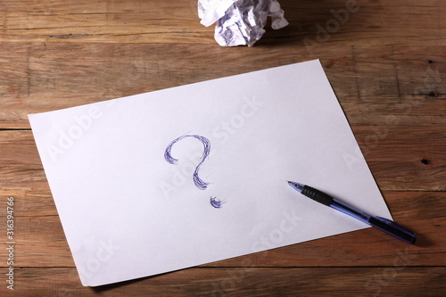 a piece of paper with a question mark on a wooden table