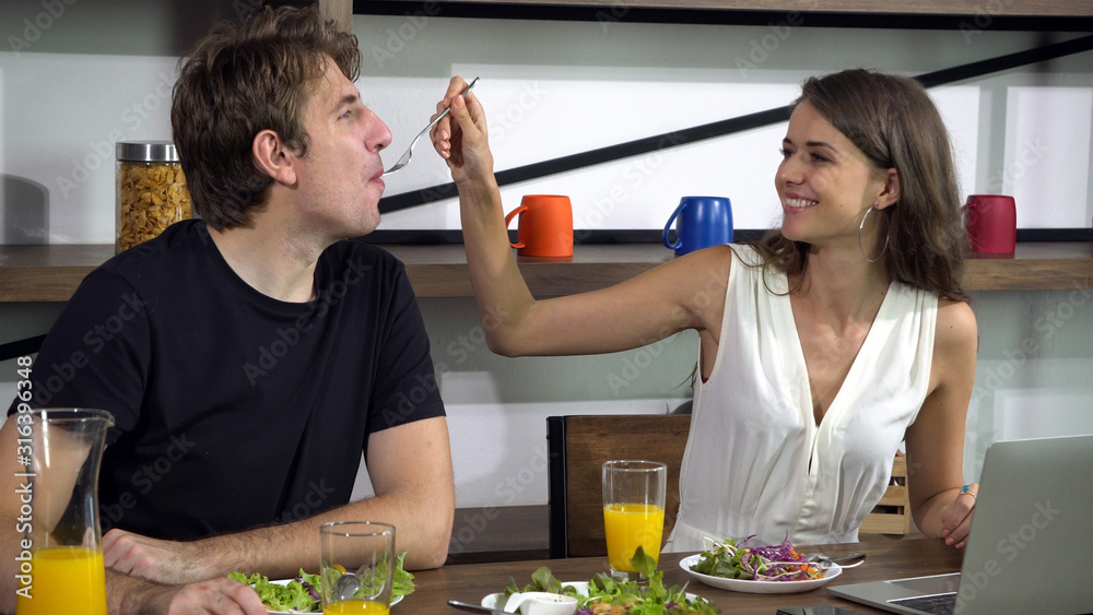 Caucasian couple feeding and have fun conversation while eating salad