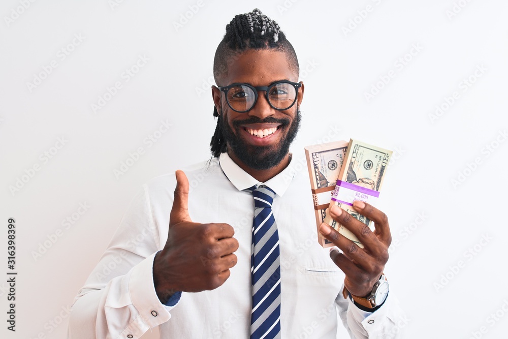 African american businessman with braids holding dollars over isolated white background happy with big smile doing ok sign, thumb up with fingers, excellent sign African american businessman with braids holding dollars over isolated white background happy with big smile doing ok sign, thumb up with fingers, excellent sign